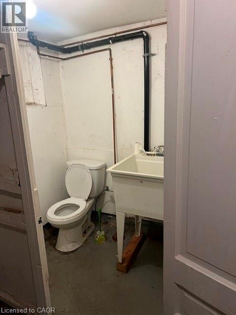 Utility space featuring exposed plumbing, a single toilet, and a stand-alone utility sink - 194 Kenilworth Avenue N, Hamilton, ON
