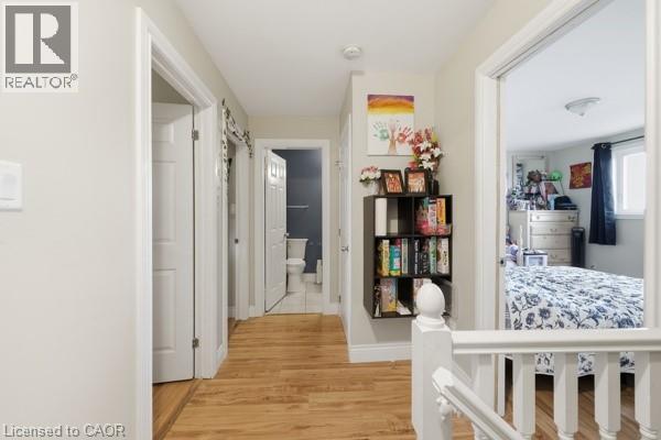 Hallway featuring wood-finish flooring, white trim, and light wall paint - 16 Harrison Avenue, Hamilton, ON