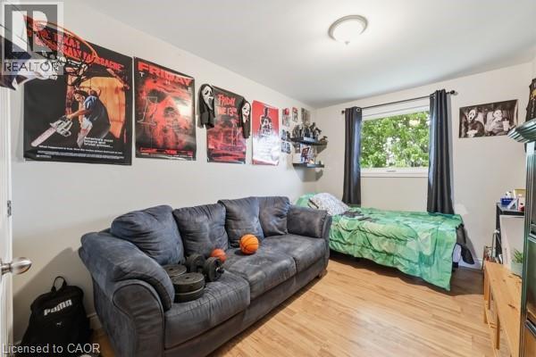 Room featuring wood-finish flooring, a window with dark curtains, and white walls - 16 Harrison Avenue, Hamilton, ON