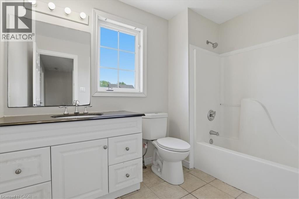 Bathroom featuring a white vanity with panel-front cabinetry, dark countertop, and brushed nickel hardware - 43 Decaro Crescent, Cambridge, ON