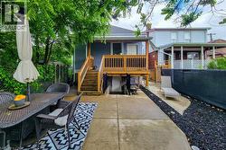 Backyard patio with concrete surfacing and a raised wood deck featuring a balustrade and stairs -
