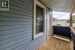 Covered porch featuring wood flooring, wood support beams, and blue horizontal siding -