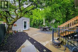 Concrete patio with a detached outbuilding featuring horizontal siding and a white entry door -