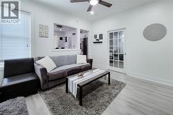 Open living space featuring light wood-finish flooring and a ceiling fan with integrated lighting -