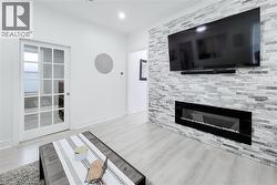 Living area featuring a floor-to-ceiling accent wall with a linear electric fireplace -
