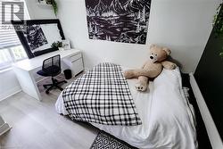 Bright bedroom featuring light wood-finish flooring and a window with blinds -