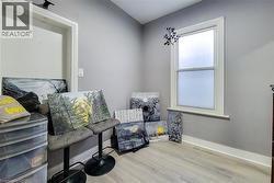 Room featuring light gray walls, white trim, and wood-finish flooring -