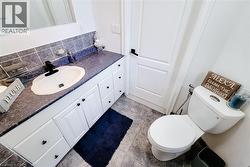 Bathroom featuring a white vanity with heart-shaped pulls, a dark countertop, and a white drop-in sink with a black faucet -