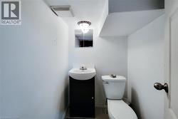 Compact powder room featuring a pedestal sink with dark wood-finish vanity, wall-mounted mirror, and overhead light fixture -