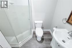 Compact bathroom featuring a corner shower with frosted glass enclosure, white toilet, and a pedestal sink with chrome fixtures -