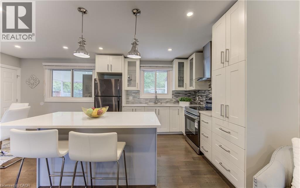 Open-concept kitchen featuring an island with a light-toned countertop and pendant lighting - 619 Forest Hill Drive, Kitchener, ON