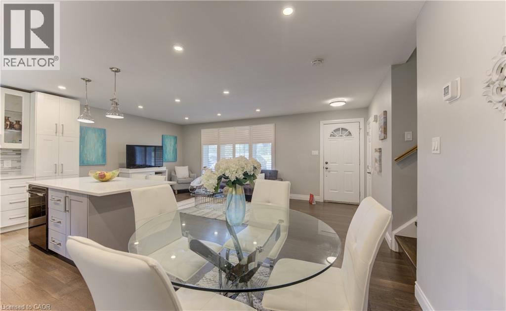 Open-concept living space featuring wood-finish flooring, recessed lighting, and a white kitchen with an island - 619 Forest Hill Drive, Kitchener, ON