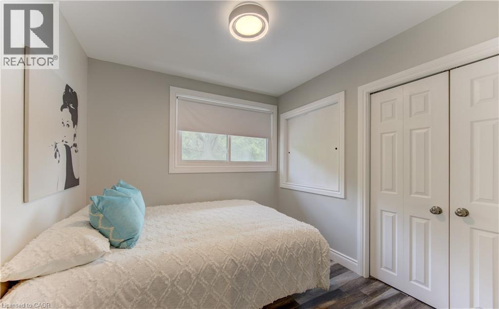 Neutral-toned room featuring wood-finish flooring, a white window frame with roller blinds, and a built-in closet with paneled bifold doors - 619 Forest Hill Drive, Kitchener, ON