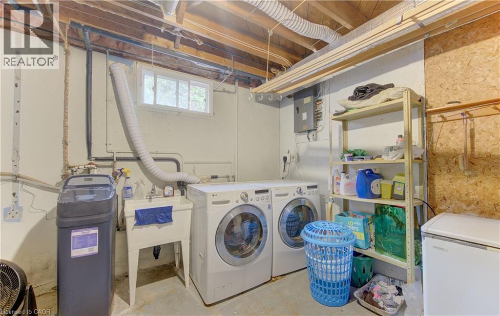 Dedicated laundry area featuring a utility sink, a window, exposed ceiling joists, and a water softener system - 619 Forest Hill Drive, Kitchener, ON