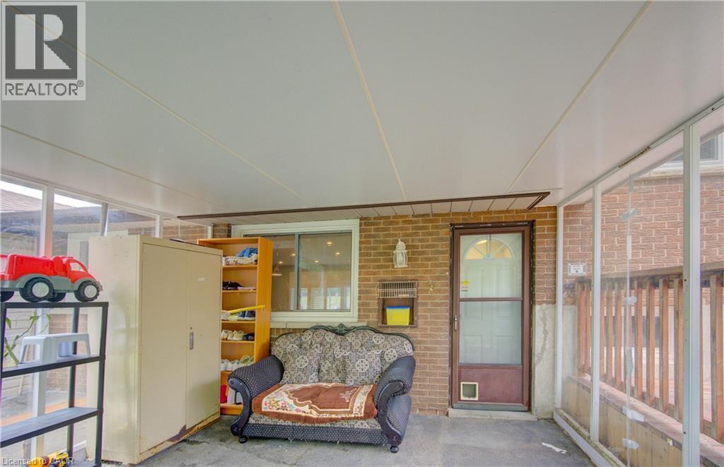 Covered patio space featuring a brick exterior wall, a white vinyl ceiling, a glass-paneled door, and a horizontal sliding window - 619 Forest Hill Drive, Kitchener, ON