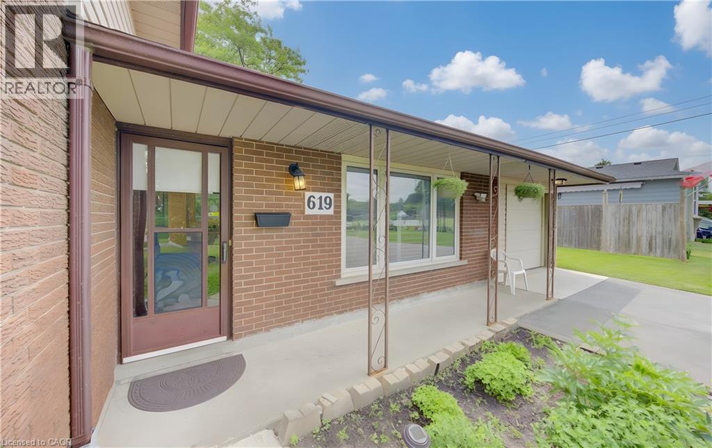 Brick exterior featuring a covered front porch with decorative iron posts and a concrete walkway - 619 Forest Hill Drive, Kitchener, ON