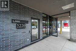 Modern commercial entrance featuring dark gray brickwork and a glass door system -