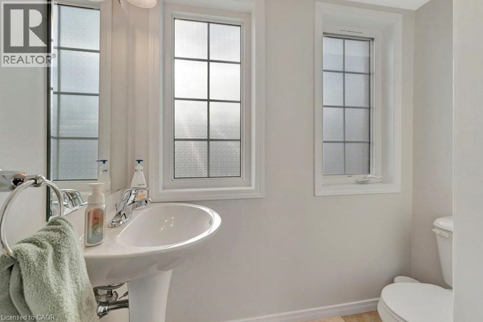 White pedestal sink with chrome faucet, flanked by two windows featuring privacy glass - 236 Rachel Crescent Unit# E, Kitchener, ON