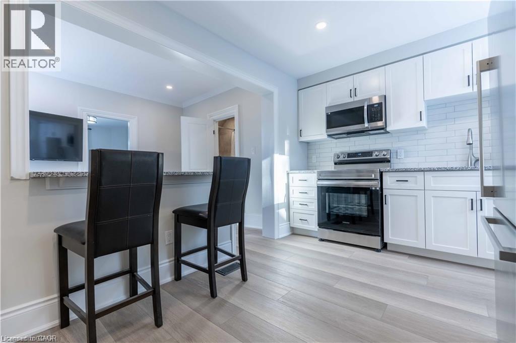 Kitchen featuring white shaker cabinetry, stainless steel appliances, and subway tile backsplash - 66 Queen Street W, Cambridge, ON
