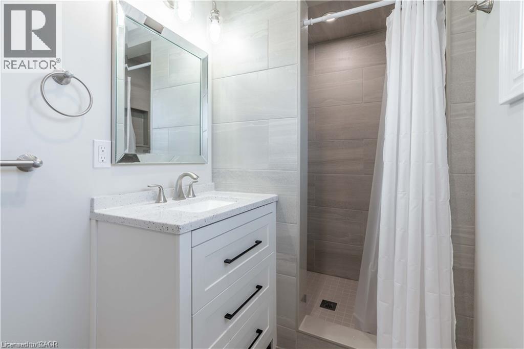 Bathroom featuring a white vanity with a speckled countertop, undermount sink, and brushed nickel faucet - 66 Queen Street W, Cambridge, ON