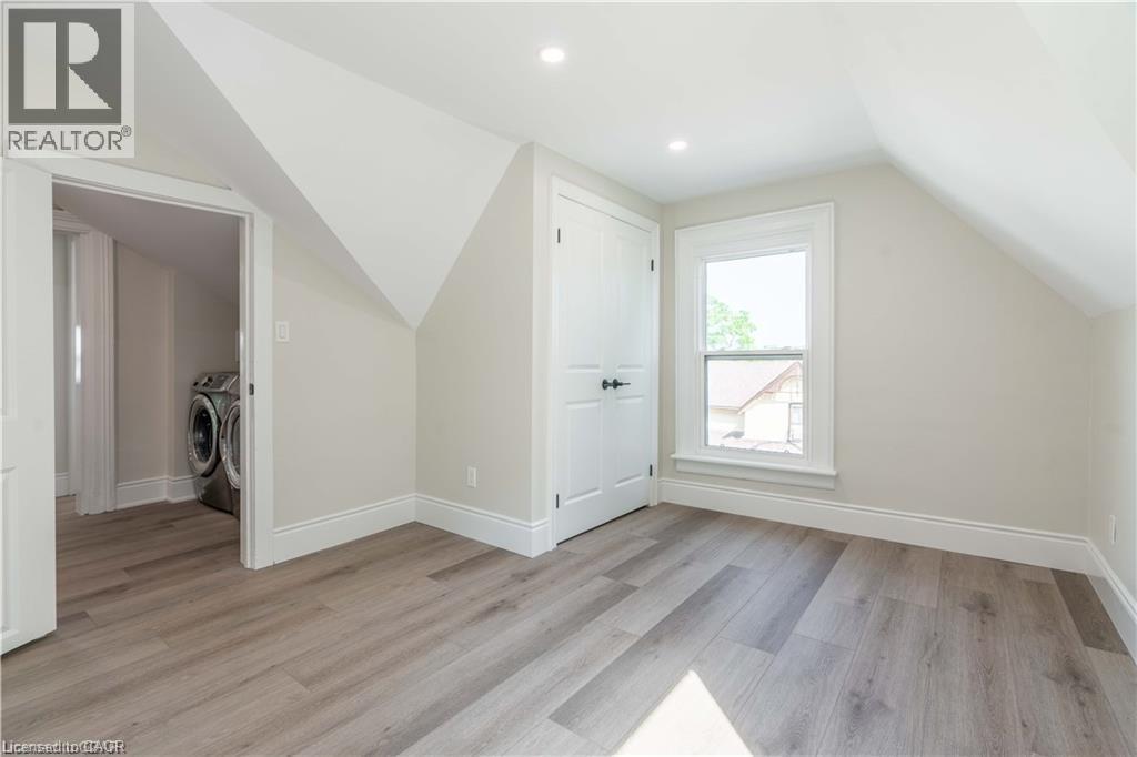 Room featuring wood-finish flooring, recessed lighting, and a window with white trim - 66 Queen Street W, Cambridge, ON