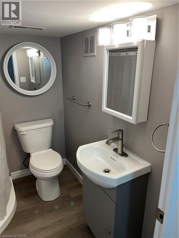 Compact bathroom featuring a white toilet, contemporary wall vanity, and white basin with a single-handle faucet - 66 Queen Street W, Cambridge, ON