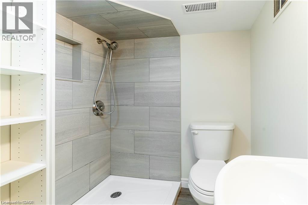 Walk-in shower featuring light grey tile surround, recessed niche, and a brushed nickel shower head - 66 Queen Street W, Cambridge, ON