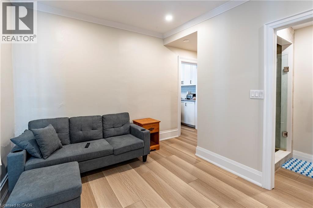 Light-toned wood-finish flooring complements neutral wall tones and white trim throughout this space - 66 Queen Street W, Cambridge, ON