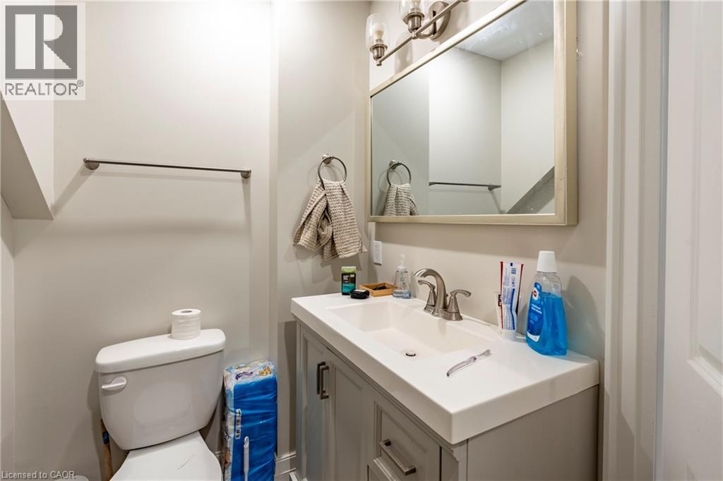 Bathroom featuring a white integrated sink, a light gray vanity with brushed nickel hardware, and a framed mirror with a three-light vanity fixture - 66 Queen Street W, Cambridge, ON