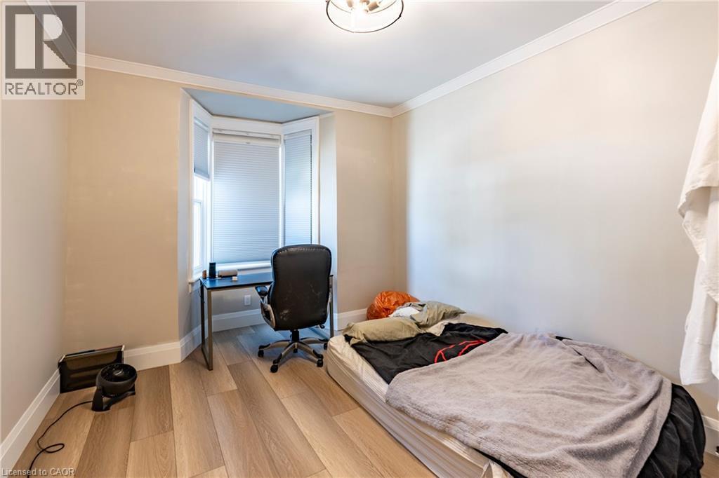 Room featuring wood-finish flooring, a bay window with blinds, and crown molding - 66 Queen Street W, Cambridge, ON