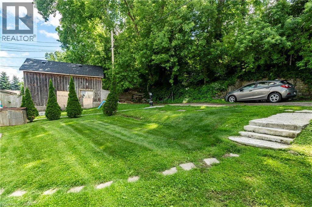 Expansive green lawn featuring concrete stepping stones and mature landscaping - 66 Queen Street W, Cambridge, ON