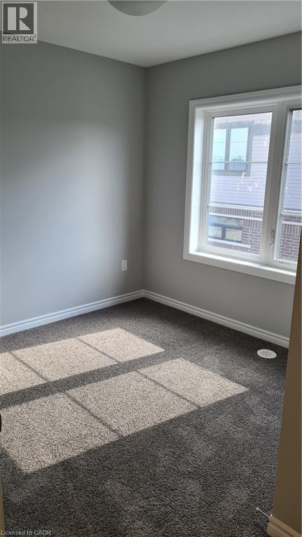 Room featuring neutral gray wall paint, dark gray carpeting, and white baseboards - 42 Wheat Lane Unit# 42, Kitchener, ON