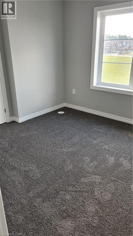 Bedroom featuring light gray wall paint, dark gray carpeting, and white baseboards - 42 Wheat Lane Unit# 42, Kitchener, ON