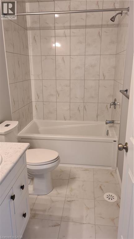 Full bathroom featuring a white porcelain tub with integrated shower, white tile surround, and coordinating tile flooring - 42 Wheat Lane Unit# 42, Kitchener, ON
