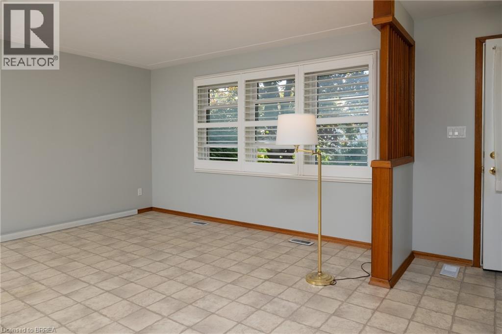 Kitchen featuring white cabinetry, a double basin stainless steel sink, a gas range with an overhead exhaust, and a window with exterior tree scenery - 156 Mutual Street N, Ingersoll, ON