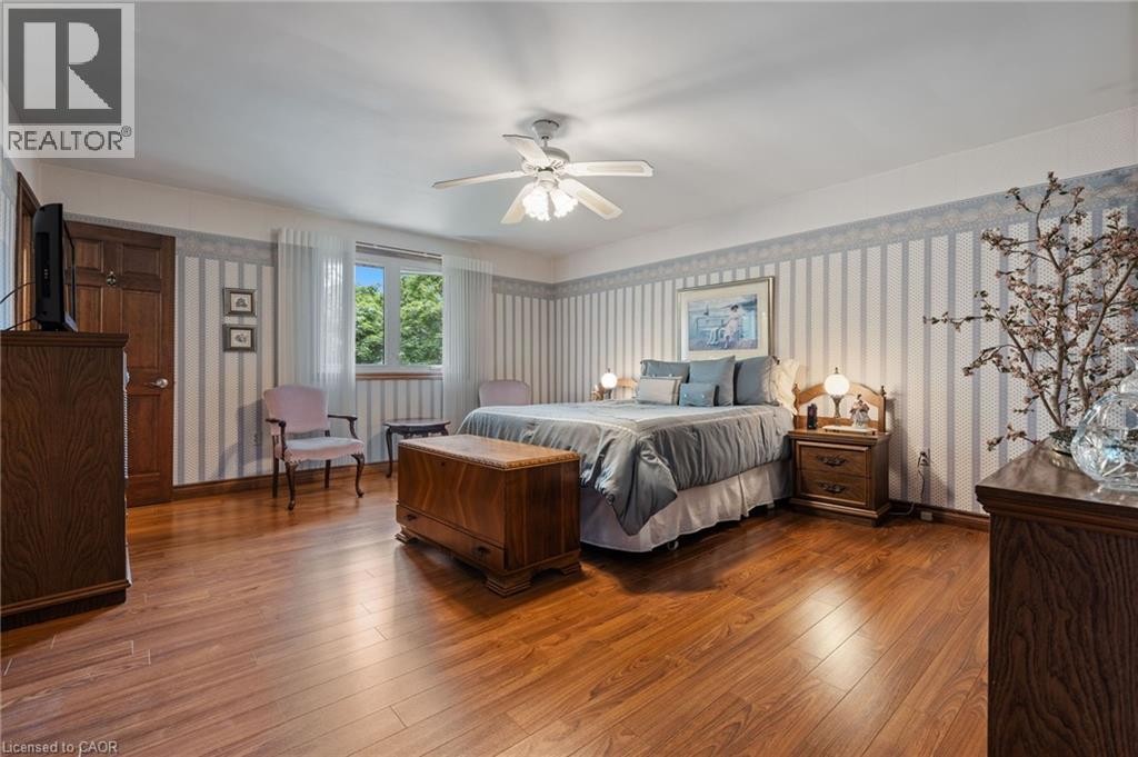 Bedroom featuring wood-finish flooring, a ceiling fan with light fixture, and a window with sheer curtains - 7 Thomson Road, Simcoe, ON