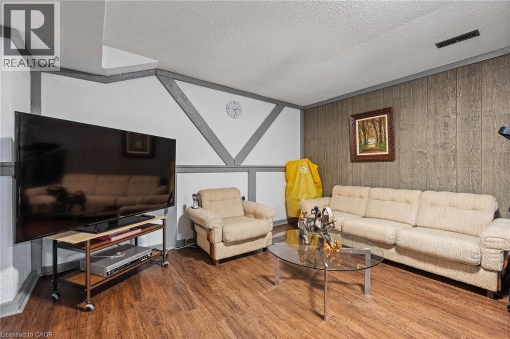 Wood-finish flooring throughout the room with a paneled accent wall - 7 Thomson Road, Simcoe, ON