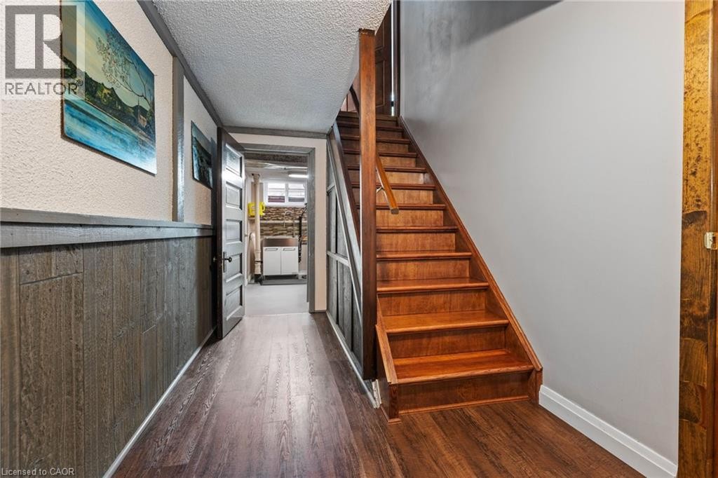 Wood-finish flooring throughout, featuring a hardwood staircase with a matching railing - 7 Thomson Road, Simcoe, ON