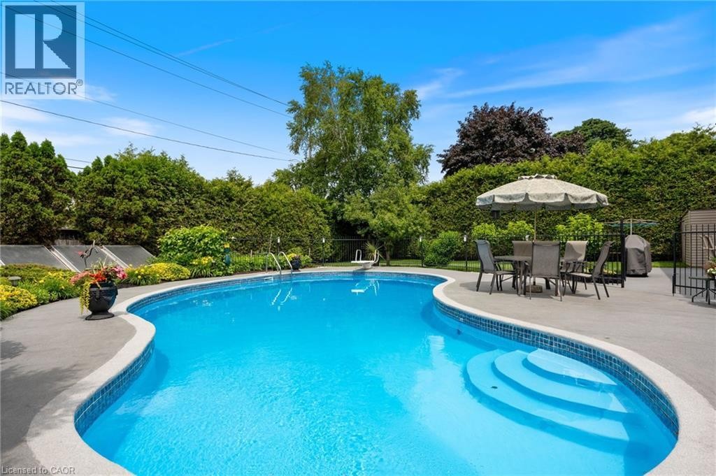 Freeform swimming pool with integrated steps and blue tile surround - 7 Thomson Road, Simcoe, ON