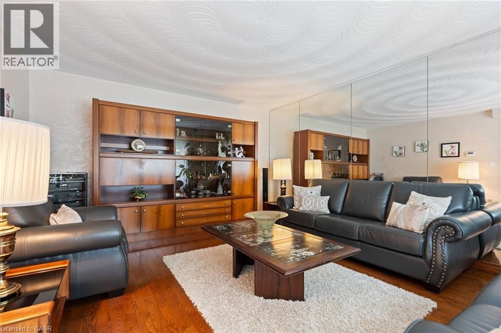 Living area featuring wood-finish flooring, a wall-mounted built-in cabinet with glass-front display, and a full-wall mirror accent - 7 Thomson Road, Simcoe, ON