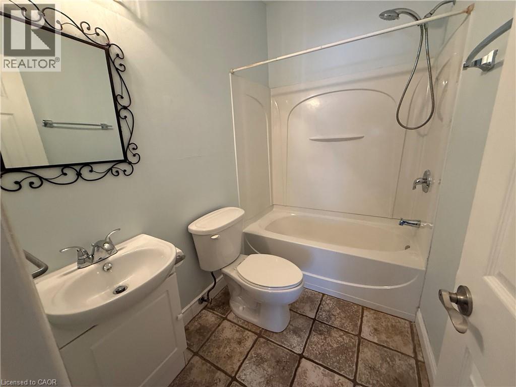 Bathroom featuring a white vanity with integrated sink, chrome faucet, and decorative mirror - 947 Main Street E, Hamilton, ON - Indoor Photo Showing Bathroom