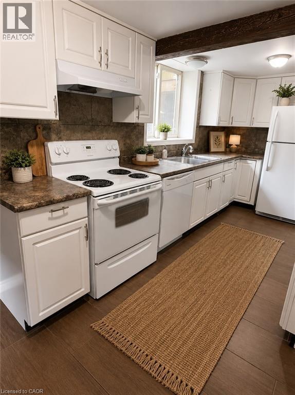 Kitchen featuring white cabinetry with brushed nickel hardware, a white electric range, and dark wood-finish flooring - 947 Main Street E, Hamilton, ON - Indoor Photo Showing Kitchen With Double Sink