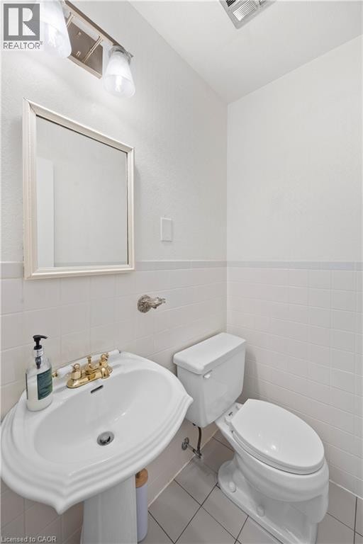 White pedestal sink featuring a brass-toned faucet, rectangular mirror, and complementary wall-mounted light fixture - 277 Blackacres Boulevard, London, ON