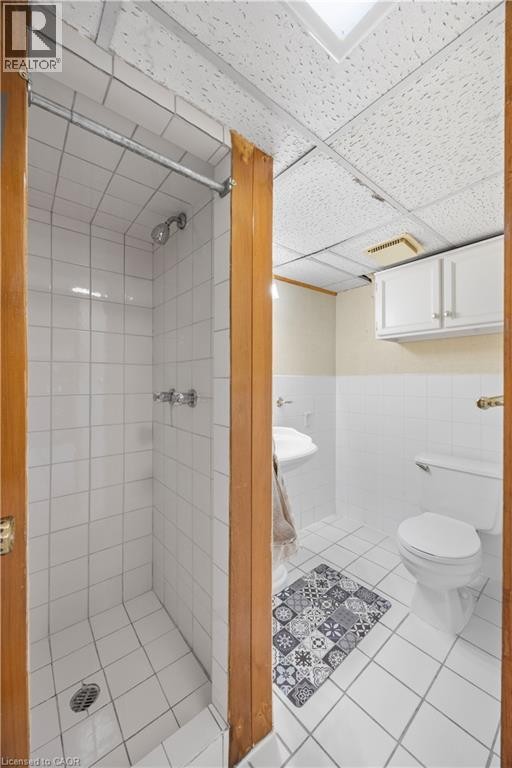 White tiled shower stall with a chrome shower head and controls - 277 Blackacres Boulevard, London, ON