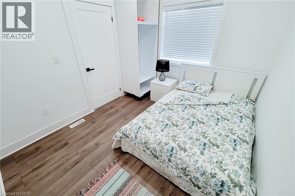 Bright room featuring wood-finish flooring, white walls, and a modern white door with a black handle - 78 Hillyard Street, Hamilton, ON