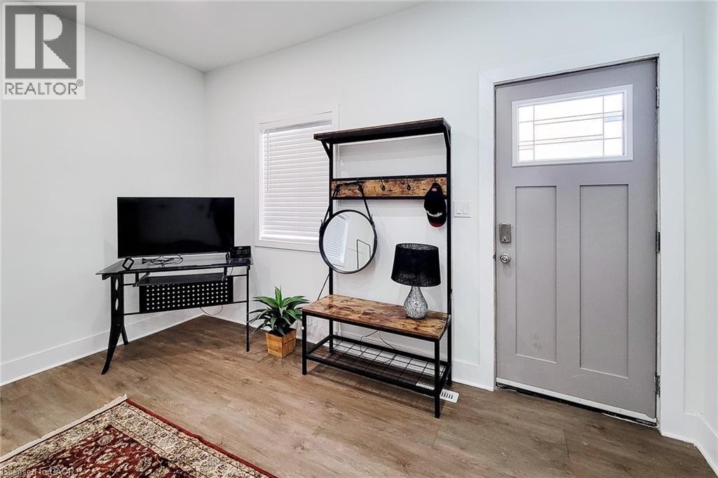 Entryway featuring wood-finish flooring, white baseboards, and a paneled door with a decorative glass insert - 78 Hillyard Street, Hamilton, ON