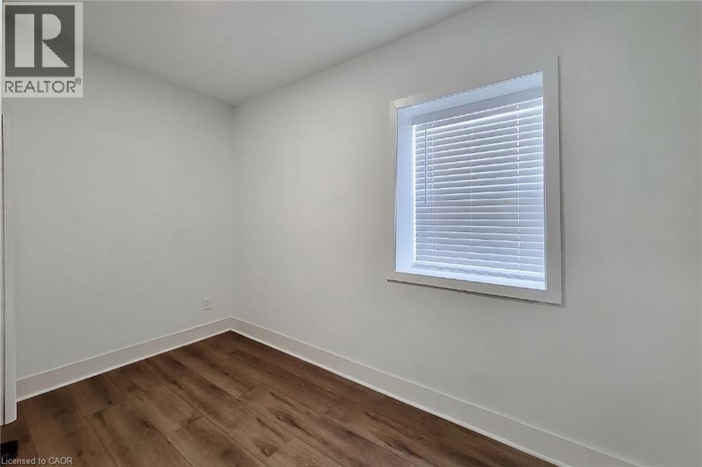 Room featuring wood-finish flooring, white baseboards, a white window frame, and blinds - 78 Hillyard Street, Hamilton, ON