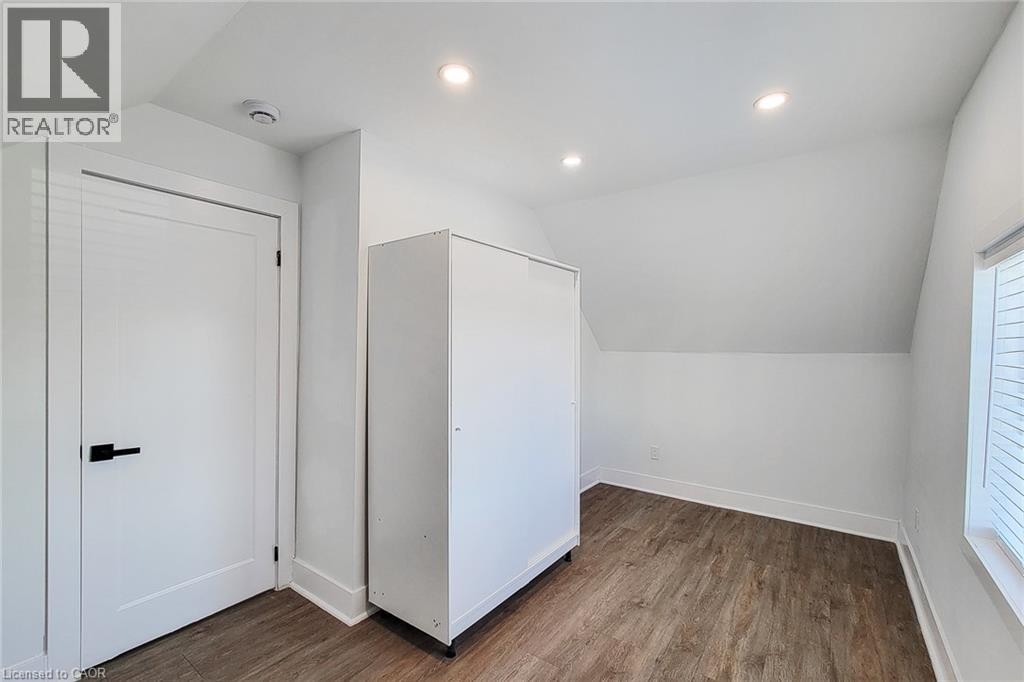 Room featuring a sloped ceiling, wood-finish flooring, recessed lighting, and a window with blinds - 78 Hillyard Street, Hamilton, ON