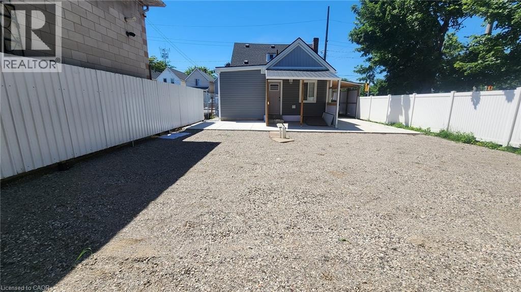 Gravel-surfaced yard featuring a new concrete patio and a multi-sided privacy fence - 78 Hillyard Street, Hamilton, ON