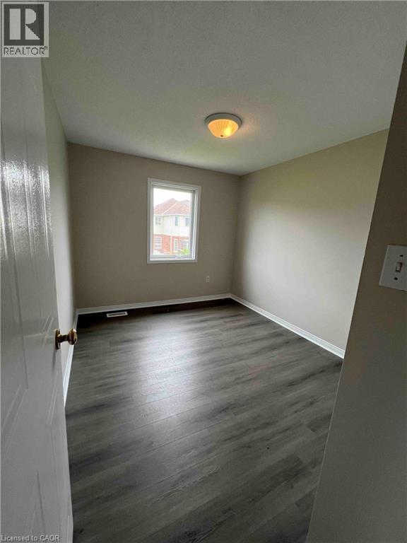Room featuring dark wood-finish flooring, neutral wall tones, and white trim - 151 Clairfields Drive E Unit# 4, Guelph, ON